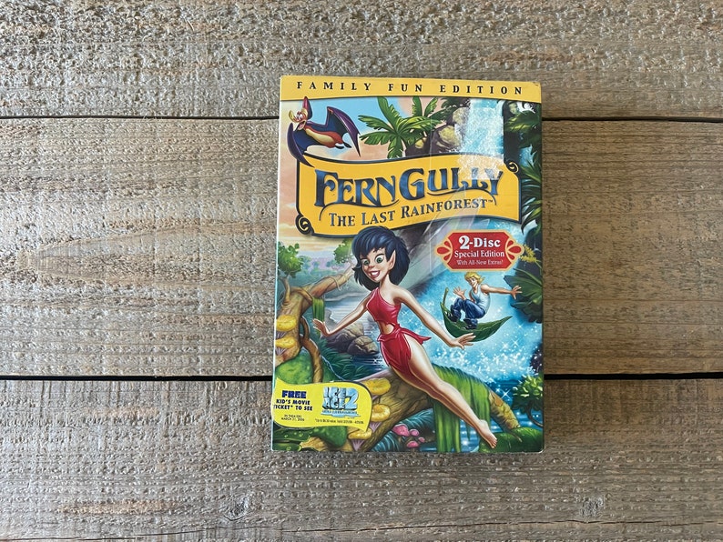 Op de afbeelding: Een DVD-hoes voor de film "FernGully: Het Laatste Regenwoud" met een label voor een familie-editie. De hoes heeft een cartoonafbeelding van een fee met groen haar en een rode jurk die op een tak staat. De tekst "2-Disc Special Edition" is zichtbaar op de hoes.