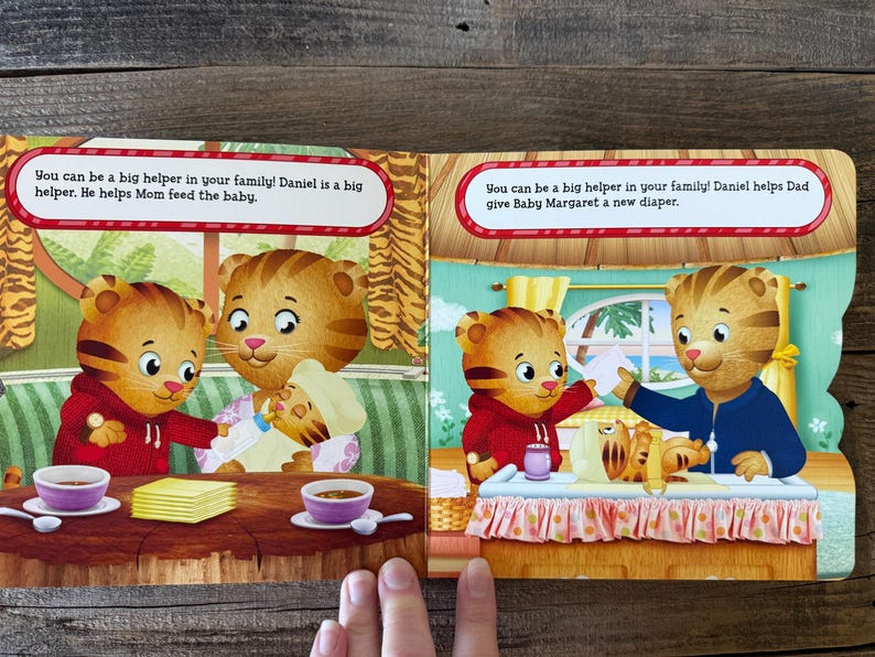 Puede incluir: Un libro infantil abierto en dos p&aacute;ginas con ilustraciones de Daniel el Tigre. El texto dice: "&iexcl;Puedes ser una gran ayuda en tu familia! Daniel es una gran ayuda. &Eacute;l ayuda a mam&aacute; a alimentar al beb&eacute;." y "&iexcl;Puedes ser una gran ayuda en tu familia! Daniel ayuda a pap&aacute; a darle a Baby Margaret un pa&ntilde;al nuevo."