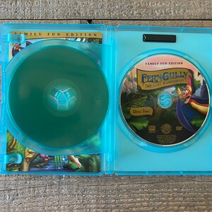 Op de afbeelding: Een blauwe DVD-doos met een transparante plastic schijfhouder. De doos heeft de tekst "Family Fun Edition" en "FernGully: The Last Rainforest" op de voorkant. De schijf is gemarkeerd met "Disc Two".