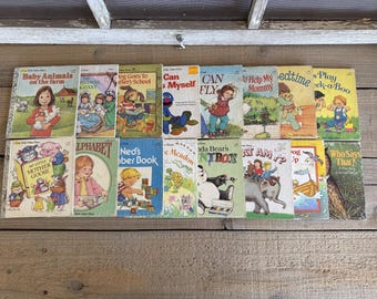 Könnte beinhalten: Eine Sammlung von Vintage-Kinderbüchern mit farbenfrohen Illustrationen. Zu den Titeln gehören "Baby Animals on the Farm", "Can Fly" und "Play Peek-a-Boo". Die Bücher sind auf einer Holzoberfläche angeordnet.