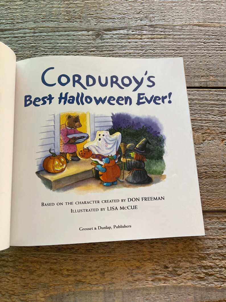 May include: A book cover featuring a brown bear dressed in a red robe holding a plate of cookies. The bear is standing in front of a house with a pumpkin on the porch. The book title is "Corduroy's Best Halloween Ever!" and the text below the title reads "Based on the character created by Don Freeman Illustrated by Lisa McCue Grosset & Dunlap, Publishers."