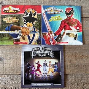 Peut inclure: Trois livres de poche Power Rangers. Le premier livre présente un Power Ranger bleu et argenté avec une épée. Le deuxième livre présente un Power Ranger rouge avec une épée. Le troisième livre présente un groupe de Power Rangers en position d'action. Les livres sont intitulés "Power Rangers Samurai : Le nouveau Ranger", "Power Rangers Megaforce : Attaque extraterrestre", et "Mighty Morphin Power Rangers : Le film".