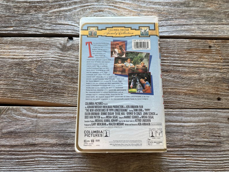 May include: A VHS tape for "The New Adventures of Pippi Longstocking" from Columbia Pictures. The cover features images from the film and the Columbia Tristar Family Collection logo. The tape is on a wooden surface.