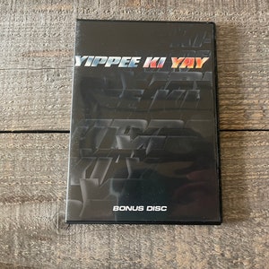 K&ouml;nnte beinhalten: Ein schwarzes DVD-Geh&auml;use mit dem Titel "YIPPEE KI YAY" in wei&szlig;er Schrift. Das Geh&auml;use enth&auml;lt auch die Worte "BONUS DISC" in wei&szlig;er Schrift.