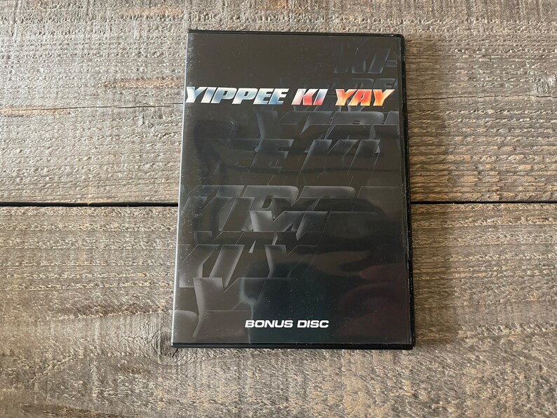 K&ouml;nnte beinhalten: Ein schwarzes DVD-Geh&auml;use mit dem Titel "YIPPEE KI YAY" in wei&szlig;er Schrift. Das Geh&auml;use enth&auml;lt auch die Worte "BONUS DISC" in wei&szlig;er Schrift.