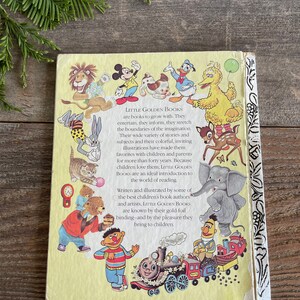 Pu&ograve; includere: La copertina posteriore di un libro Little Golden Book con illustrazioni di personaggi popolari per bambini come Topolino, Paperino, Big Bird e un elefante. Il testo sulla copertina recita "Little Golden Books are books to grow with. They entertain, they inform, they stretch the boundaries of the imagination."