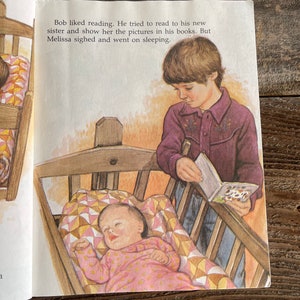 Pu&ograve; includere: Un bambino legge un libro alla sua sorellina che dorme in una culla. La culla ha una trapunta colorata. Il bambino indossa una camicia viola e jeans. Il testo nell'immagine dice: "A Bob piaceva leggere. Ha cercato di leggere alla sua nuova sorella e mostrarle le immagini nei suoi libri. Ma Melissa ha sospirato e ha continuato a dormire."