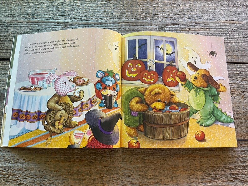 May include: A children's book illustration of a Halloween party with stuffed animals dressed in costumes. A pink bunny with a blue bow, a brown bear wearing a green shirt, a blue bear with a black hat, and a brown dog wearing a green costume. The animals are gathered around a table with food and drinks. There are pumpkins and apples on the table. The text on the page reads "Cadbury thought and thought. He thought all through the party. It was a really fun party,  most  they gobbled for apples and carved jack-o-lanterns and ate cookies and punch."