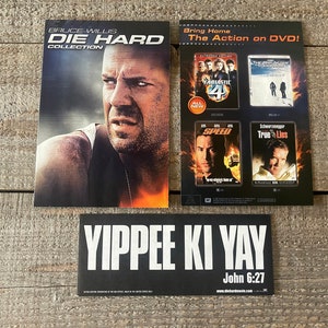 K&ouml;nnte beinhalten: Ein schwarz-wei&szlig;er Aufkleber mit dem Text "YIPPEE KI YAY" und "John 6:27" in wei&szlig;er Schrift. Der Aufkleber wirbt f&uuml;r die "Die Hard Collection" auf DVD. Das Bild zeigt auch ein DVD-Cover mit Bruce Willis als John McClane aus dem Film "Die Hard".