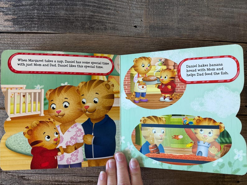 Puede incluir: Libro abierto con ilustraciones del programa infantil Daniel Tiger's Neighborhood. Las p&aacute;ginas muestran a Daniel Tiger con sus padres, y el texto dice: "Cuando Margaret toma una siesta, Daniel tiene un tiempo especial con mam&aacute; y pap&aacute;."