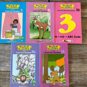 Może przedstawiać: Kolekcja książek dla dzieci zatytułowanych "Sing, Spell, Read & Write". Książki zawierają kolorowe ilustracje i tekst, z tytułami takimi jak "Grand Tour Storybook" i "Phonetic Storybook Reader". Książki są przeznaczone dla początkujących czytelników.
