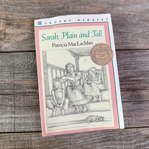 Może przedstawiać: Książka w miękkiej okładce zatytułowana "Sarah, Plain and Tall" autorstwa Patricii MacLachlan. Okładka przedstawia czarno-białą ilustrację kobiety i dwojga dzieci na werandzie. Do okładki przymocowany jest złoty medal.