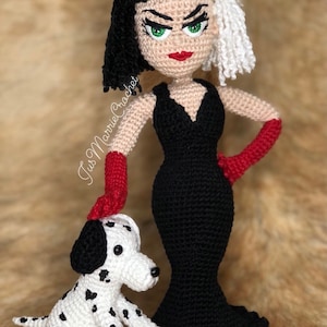 May include: A crocheted doll of Cruella de Vil from Disney's 101 Dalmatians, wearing a black dress and red gloves, standing next to a crocheted Dalmatian puppy.