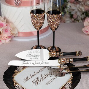 May include: A black cake server with a gold and rose gold trim and the text "Mr. & Mrs. Holsinger 04/22/2023 Together is my favorite place to be" and a black and gold cake knife with the text "Michael & Juan Holsing 04/22/2023".