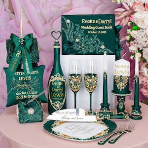 May include: An elegant emerald green wedding set featuring a guest book, champagne bottle, flutes, candles, and decorative accents. The set includes personalized details with gold embellishments and the names Evette & Darryl Lewis, with the date October 17, 2025.