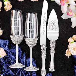 May include: A wedding cake cutting set with two champagne flutes and a cake knife. The flutes and knife are decorated with rhinestones. The flutes are engraved with the names "Khmer" and "Banpre" and the date "07. 2022". The cake knife is engraved with "Mr. & Mrs. Burke" and the date "07/02/2022". The knife also has the text "You will Forever be my Always".