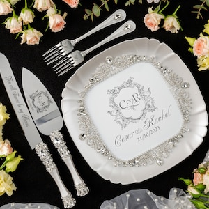 May include: A wedding cake serving set with a decorative plate. The set includes a cake knife and server, two forks, and a square plate. The plate and handles are embellished with rhinestones. The plate has the names "Cesar & Rachel" and the date "21/10/2023".
