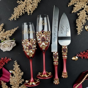 May include: Burgundy wedding champagne flutes with gold lettering and crystal embellishments, and a matching cake knife with the text "Forever blessed and happy" and "Always Kira".