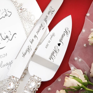 May include: A silver cake cutting set with rhinestone handles. The knife has the inscription "You will forever be my Always" and the server has the inscription "Ramah Nabila August 19, 2024".