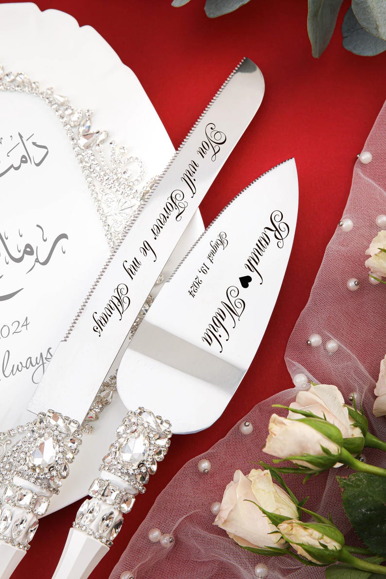 May include: A silver cake cutting set with rhinestone handles. The knife has the inscription "You will forever be my Always" and the server has the inscription "Ramah Nabila August 19, 2024".