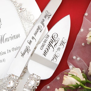 May include: A white cake server set with rhinestone handles. The server blades are engraved with the text "Mr. & Mrs. Faheem 03/10/2023" and "Forever be my Always Mariam You In Pairs 8:8)".