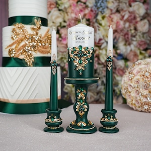 May include: Three green pillar candles with gold accents and rhinestones. The center candle has a white label with the text "LaToya & Garfield Barnett 07.23.2023".