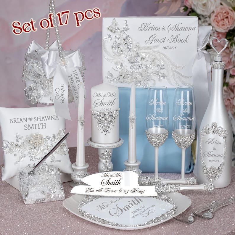 May include: A wedding ceremony set with 17 pieces, including a guest book, two champagne flutes, a champagne bottle, a cake knife and server, two candles, a pillow, a ring bearer pillow, and a decorative box. The set is decorated with rhinestones and the text "Brian & Shawna" and "Mr. & Mrs. Smith".