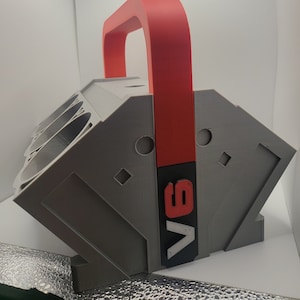 May include: A gray tool organizer with a red handle and the word "V8" printed on the side. The organizer has multiple compartments for storing tools.