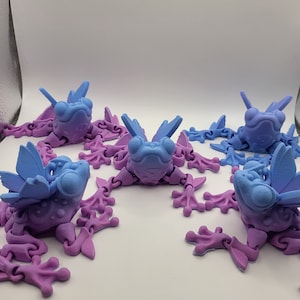 May include: Five purple and blue articulated frog toys with wings. The frogs are made of plastic and have a detailed design.