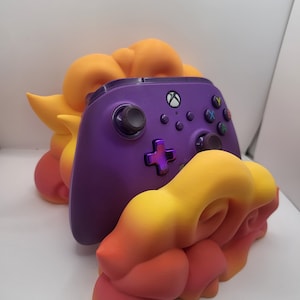 May include: Purple Xbox controller resting in a 3D printed orange, yellow, and red cloud-shaped stand.