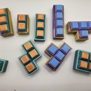 May include: A set of 10 colorful Tetris-shaped blocks. The blocks are made of plastic and have a textured surface. The blocks are in various colors, including blue, green, and orange.