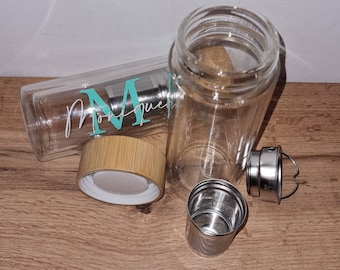 May include: Two glass tea bottles with bamboo lids and stainless steel infusers. One bottle has a teal monogram "M" and the name "Monique" on it.