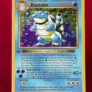 May include: A Pokémon trading card featuring Blastoise, a blue turtle-like creature. The card has a blue and yellow border with text describing the character's abilities, including "Hydro Pump." The card is 5' 3" long and weighs 189 lbs.