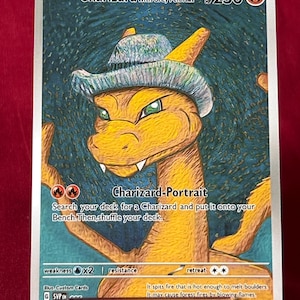Op de afbeelding: Een Charizard-verzamelkaart met een portret van het personage met een grijze vilten hoed. De kaart heeft een blauwgroene achtergrond met de tekst "Charizard with Grey Felt Hat" en "Charizard-Portrait". De kaart wordt in een doorzichtige plastic houder gehouden.