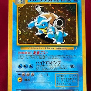 Peut inclure: Carte de collection Pokémon avec Blastoise, créature bleue en forme de tortue. La carte a du texte japonais, un niveau de 52 et 100 PV. Le fond de la carte est un motif moucheté avec une bordure bleue et jaune.