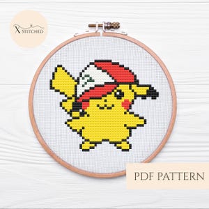 Puede incluir: Un patrón de punto de cruz de Pikachu con un gorro rojo y blanco, exhibido en un bastidor de bordado de madera. El diseño es amarillo, negro y rojo. El texto "PDF PATTERN" está debajo del bastidor. El logo "X Stitched" está en la esquina superior izquierda.
