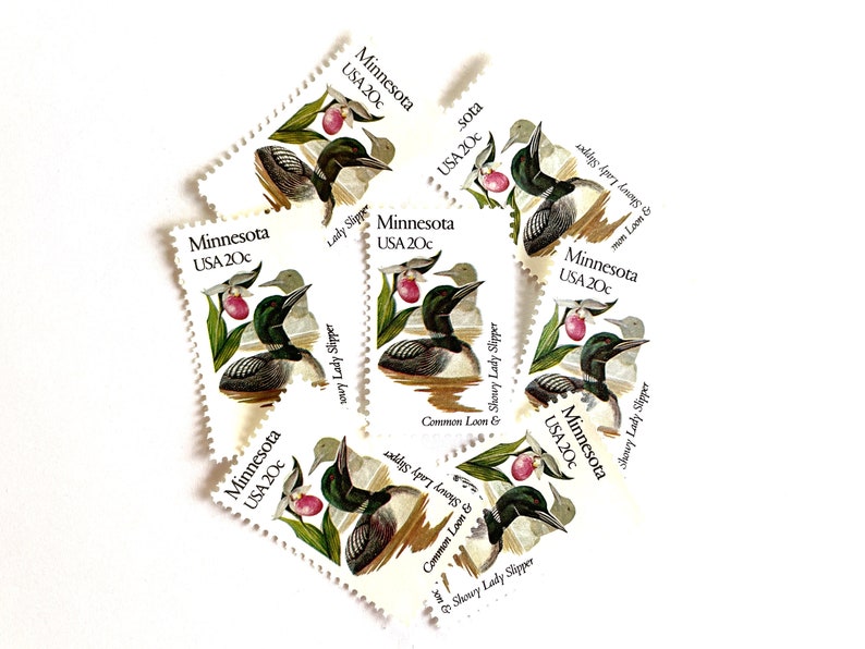 May include: Six vintage United States postage stamps featuring a common loon and a showy lady slipper flower. The stamps are from the state of Minnesota and are each worth 20 cents.