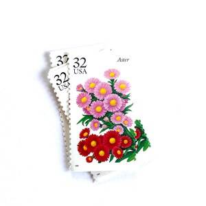 May include: Three 32 cent USA postage stamps featuring a bouquet of pink and red aster flowers. The stamp reads "Aster" at the top.