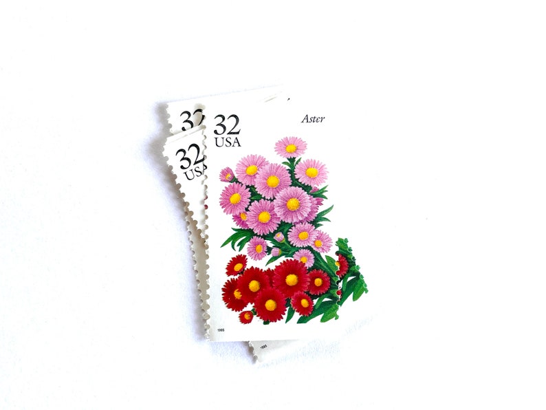 May include: Three 32 cent USA postage stamps featuring a bouquet of pink and red aster flowers. The stamp reads "Aster" at the top.