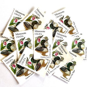 May include: A collection of vintage Minnesota state commemorative postage stamps featuring a common loon and a showy lady slipper. Each stamp is white with green and pink illustrations and the text "Minnesota USA 20c".