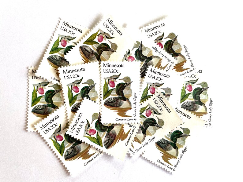 May include: A collection of vintage Minnesota state commemorative postage stamps featuring a common loon and a showy lady slipper. Each stamp is white with green and pink illustrations and the text "Minnesota USA 20c".