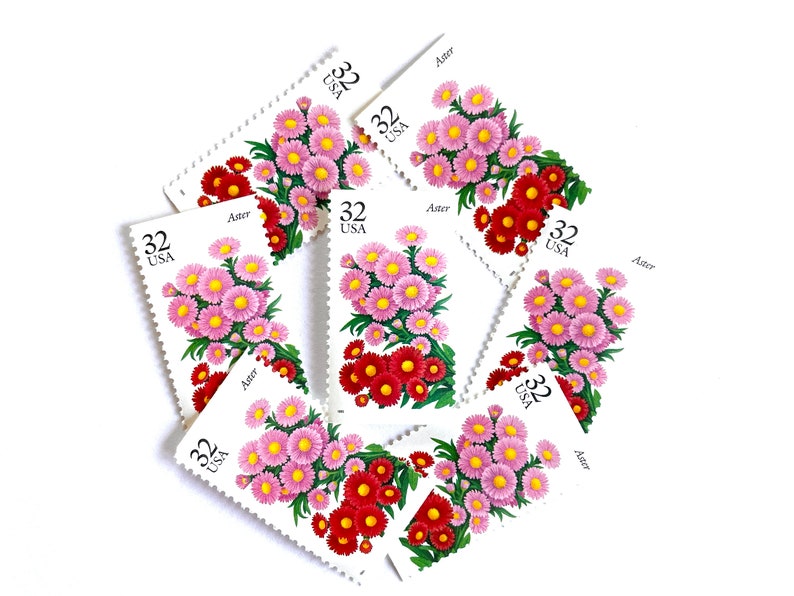 May include: A collection of eight vintage US postage stamps featuring a cluster of pink and red aster flowers. Each stamp has the text "32 USA" and "Aster" printed on it.