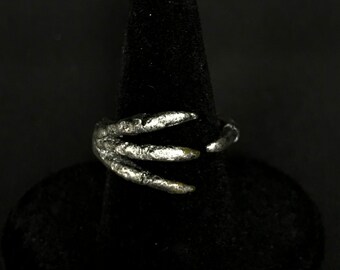 May include: A silver ring shaped like a claw with three sharp points.