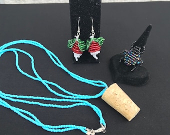 Pendientes de cuentas de rábano, collar de cuentas azules con colgante de corcho y anillo de escarabajo con cuentas negras y multicolores.