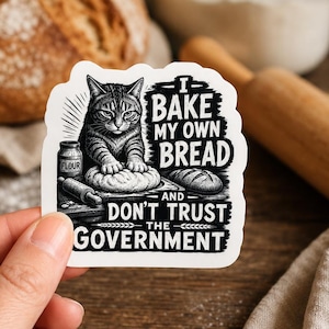 May include: A white die-cut sticker featuring a black and white illustration of a cat kneading dough. The text reads: I BAKE MY OWN BREAD AND DON'T TRUST THE GOVERNMENT. A small jar labeled FLOUR and a rolling pin are visible next to the cat.