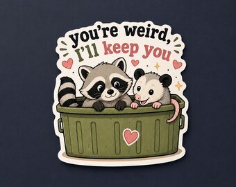 Può includere: Un adesivo con un procione e un opossum disegnati all'interno di un contenitore di plastica verde. Il testo sopra recita you're weird, I'll keep you in caratteri neri e rossi, circondato da piccoli cuori rosa e accenti a forma di stella gialla.