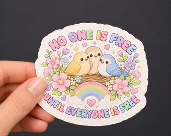 Può includere: Un adesivo fustellato con tre piccoli uccellini in un nido circondati da fiori rosa, viola e bianchi, un arcobaleno e cuori. Il testo NO ONE IS FREE UNTIL EVERYONE IS FREE è scritto in lettere maiuscole colorate e arrotondate.