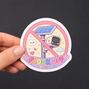 May include: A circular sticker featuring a security camera with a solar panel, surrounded by pastel hearts, stars, and clouds. A pink diagonal line crosses the center. The text FLOCK OFF is printed in colorful letters at the bottom of the sticker.