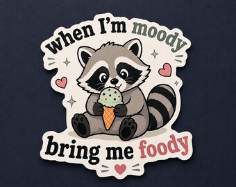 Può includere: Un adesivo fustellato raffigurante un procione dei cartoni animati con pelliccia grigia e nera che tiene in mano un cono gelato verde menta. Il testo "when I'm moody bring me foody" è scritto in nero e rosso, circondato da cuoricini rosa e stelle.