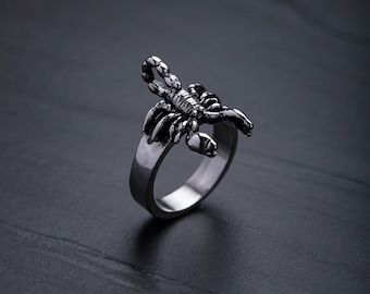 May include: A silver ring featuring a scorpion design. The scorpion is detailed and has a textured finish.